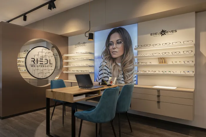 Moderne Optiker-Filiale mit Brillenregalen, Werbeposter und Beratungstisch mit Laptop