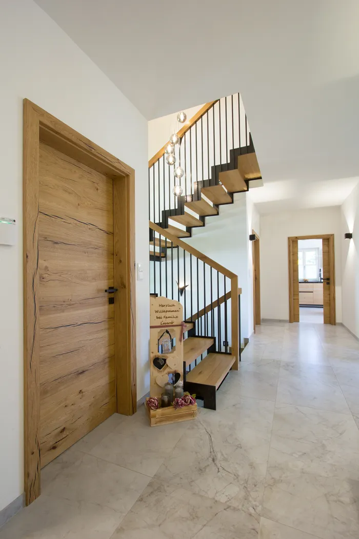 Heller Flur mit Holztreppe, modernen Leuchten und Dekoration aus Holz im Eingangsbereich