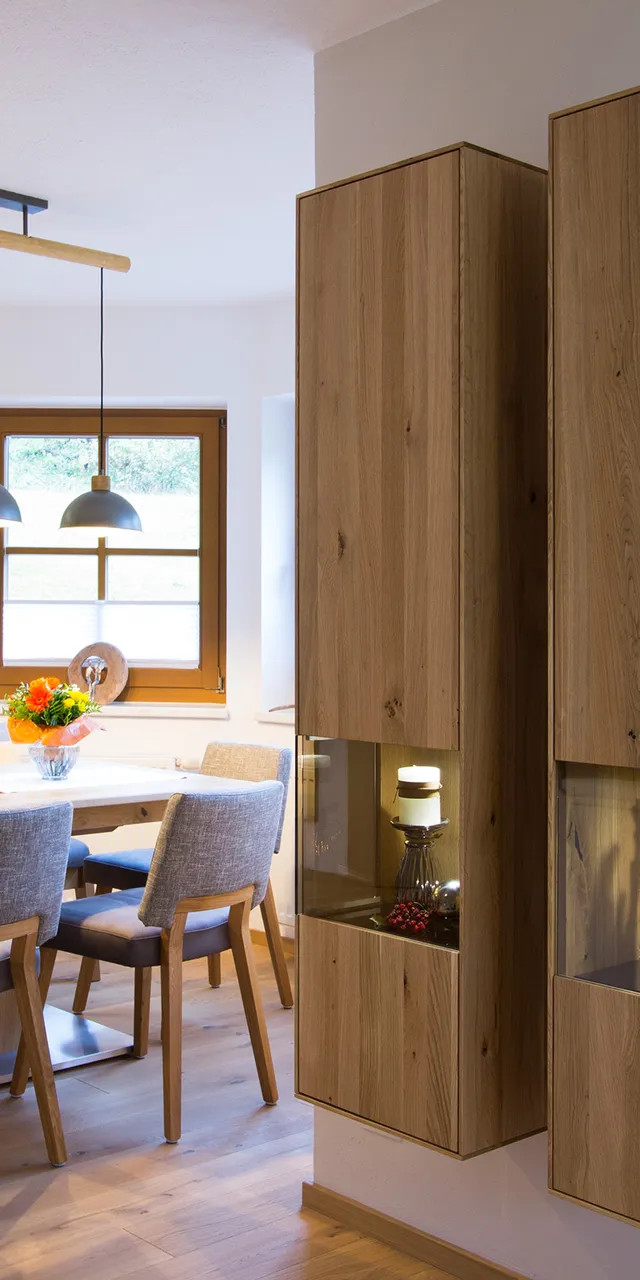 Moderne Esszimmerküche mit Holzmöbeln, grauen Stühlen und dekorativen Hängeleuchten