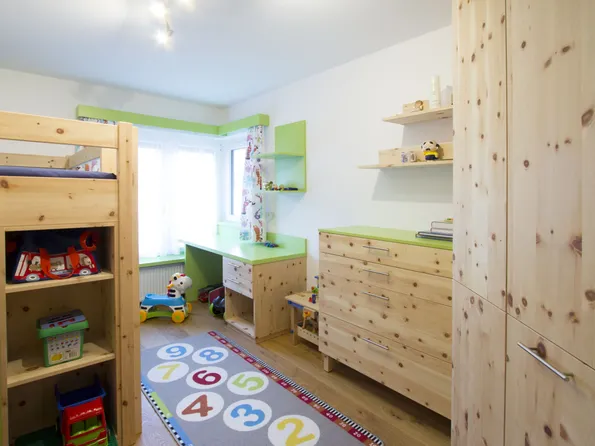 Helles Kinderzimmer mit Holzmöbeln, Etagenbett, Spielzeugregal und buntem Zahlen-Teppich