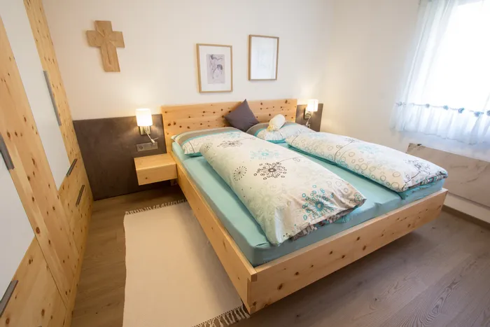 Modernes Schlafzimmer mit Doppelbett aus hellem Holz und gemusterten Bettdecken