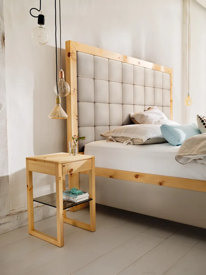 Modernes Schlafzimmer mit Polsterbett, Nachttisch aus Holz und Hängelampen im skandinavischen Design