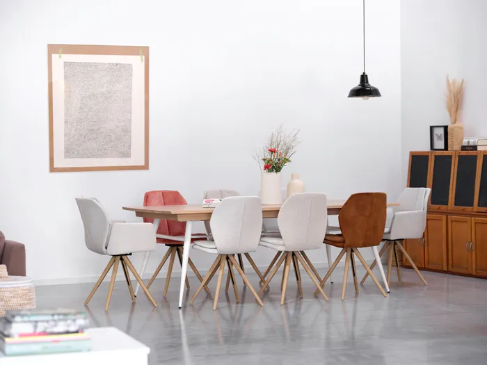 Moderner Esstisch mit gemischten Polsterstühlen und Blumen in heller Wohnzimmereinrichtung