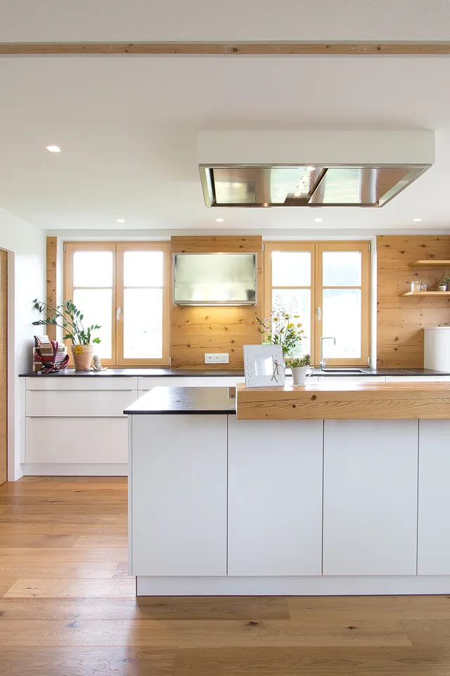 Moderne helle Küche mit Kochinsel, Holzboden und großen Fenstern