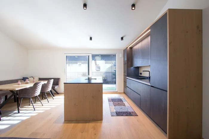 Moderne offene Küche mit dunklen Schränken, Kochinsel und Essbereich mit Eckbank