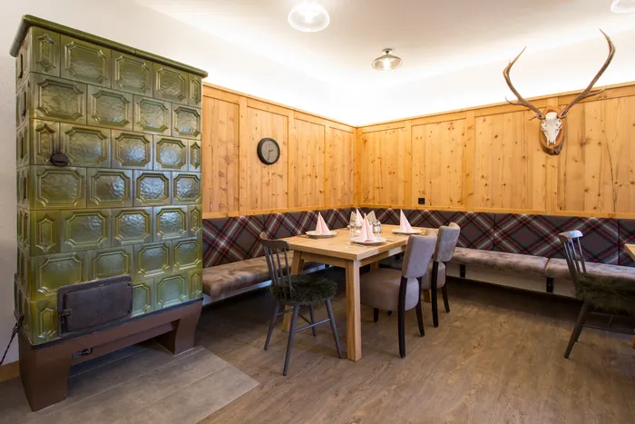 Gemütliche Stube mit Kachelofen, Holzwänden und gedecktem Esstisch im Alpenstil