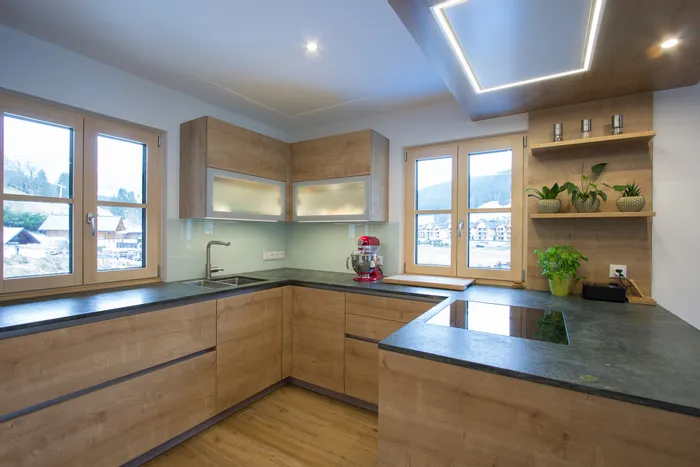 Moderne Einbauküche mit Holzfronten, Induktionskochfeld und Küchenmaschine bei Tageslicht