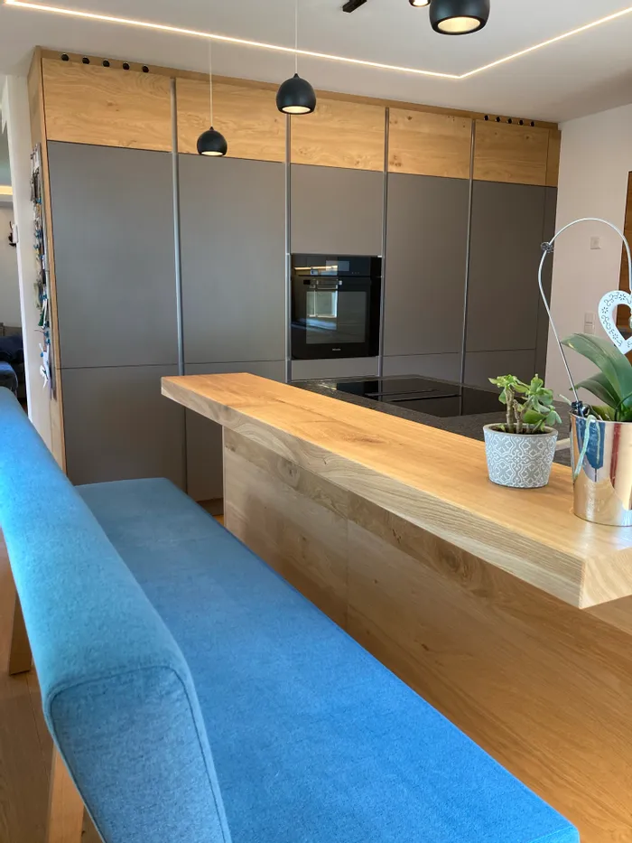 Moderne Küche mit grauen Schränken, Holzakzenten und blauer Bank am Küchenblock