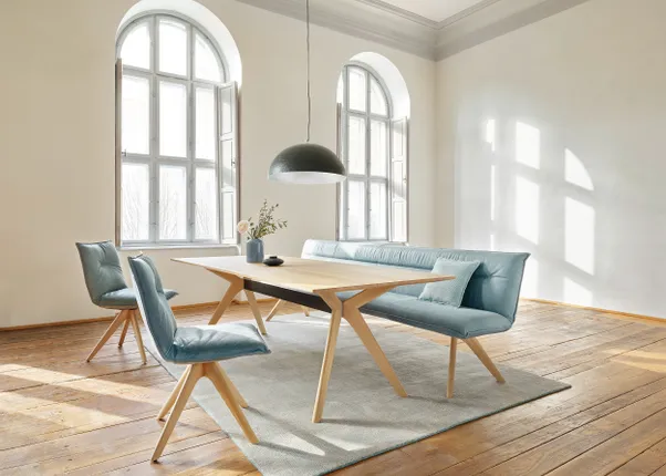 Helles Esszimmer mit Holztisch, blauen Polsterstühlen und großem Bogenfenster