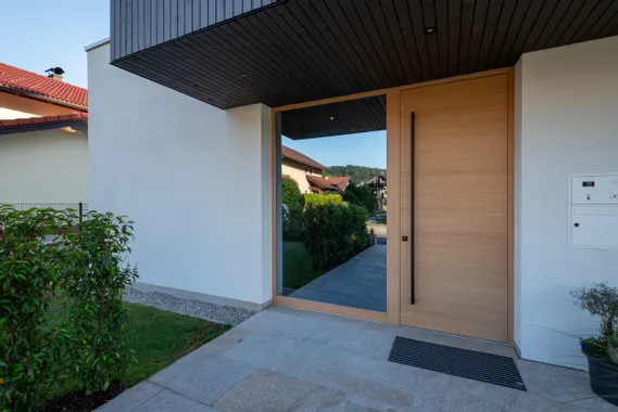 Moderne Haustür aus Holz mit großem Seitenglas und gepflegtem Hauseingang