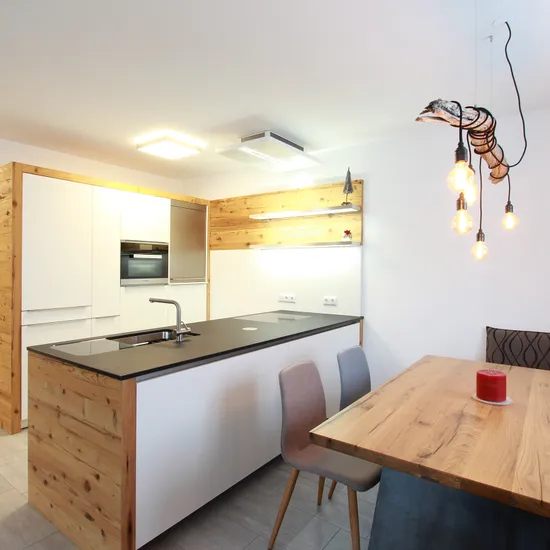 Moderne Küche mit Holzverkleidung, Kücheninsel, Esstisch und Hängelampen im skandinavischen Stil