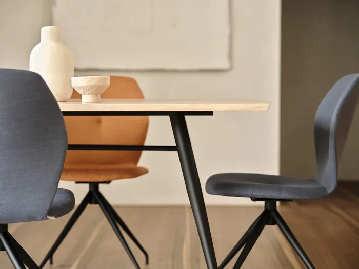 Moderner Esstisch mit minimalistischer Dekoration und gepolsterten Stühlen in Blau und Orange