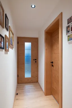 Heller Flur mit Holztüren, Spotbeleuchtung und Familienfotos an den Wänden