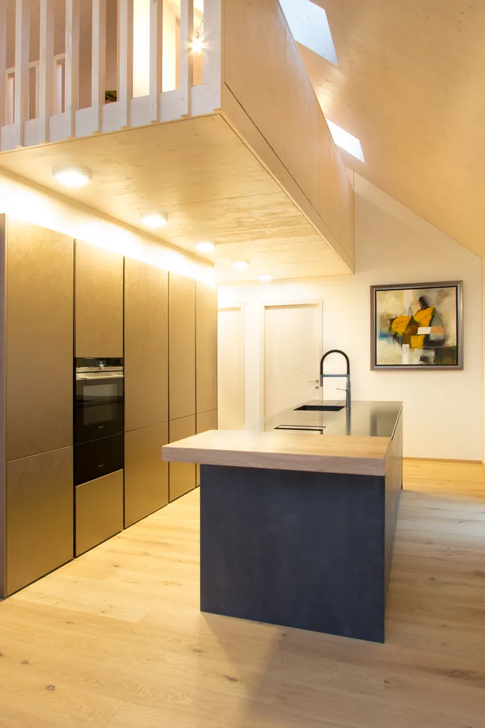 Moderne offene Küche mit Holzverkleidung, Kochinsel und Einbauschränken in Goldoptik