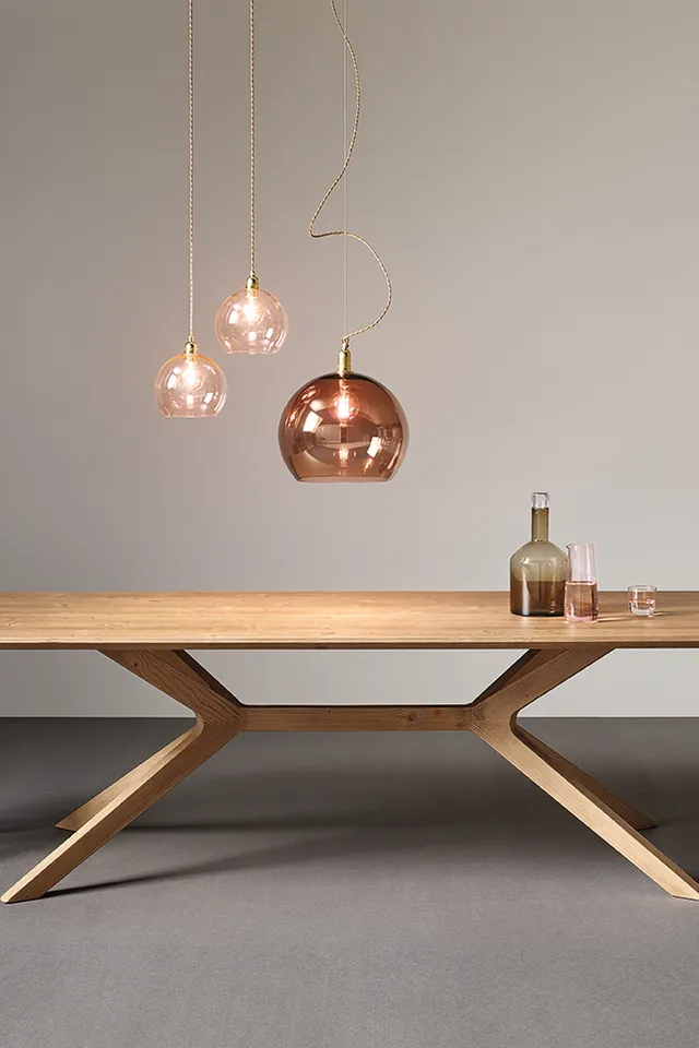 Moderner Esstisch aus Holz mit zwei grauen Stühlen und Hängelampen in Kupferoptik