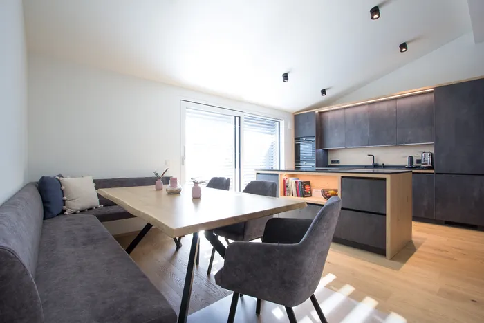 Moderne Wohnküche mit grauen Schränken, Essbereich und großem Fenster mit Tageslicht