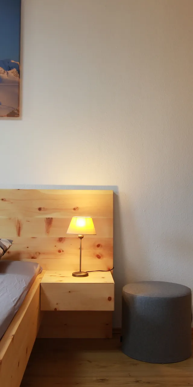 Modernes Schlafzimmer mit Holzbett, Nachttischlampe und Einbauschrank aus Holz