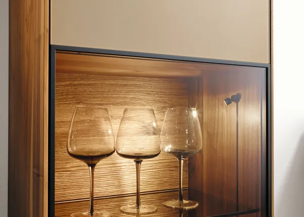 Drei Weingläser in einem beleuchteten Holzvitrinenschrank auf Glasboden