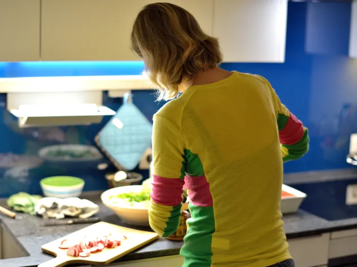 Frau in bunter Kleidung bereitet Gemüse in moderner Küche vor