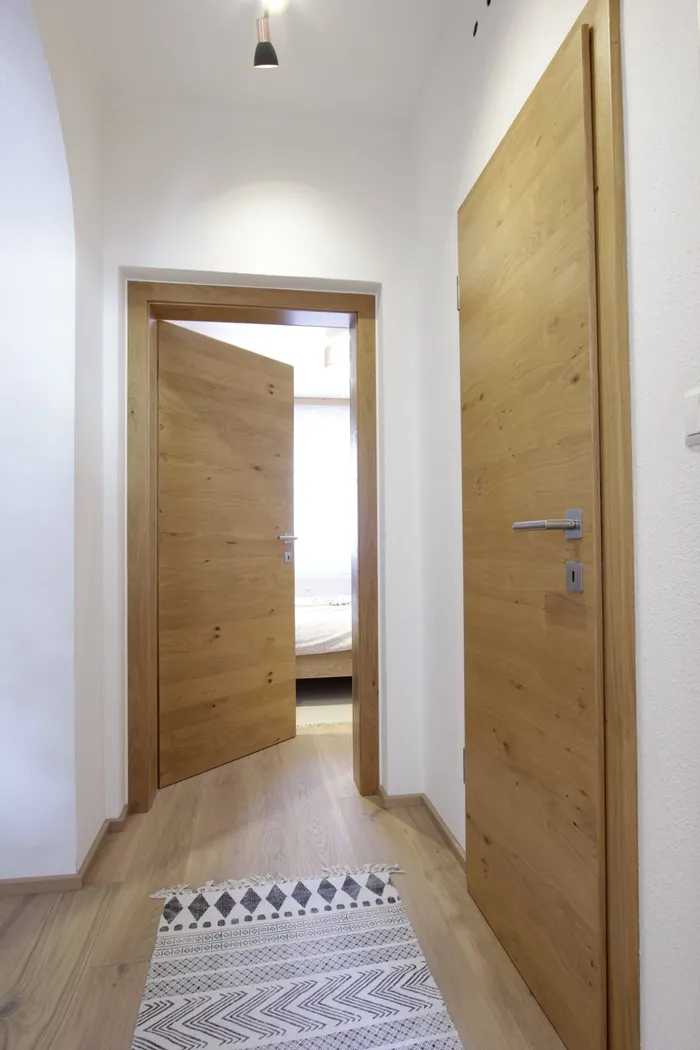 Moderner Flur mit Holzboden, geöffneter Tür zum Schlafzimmer und hellem Wandteppich