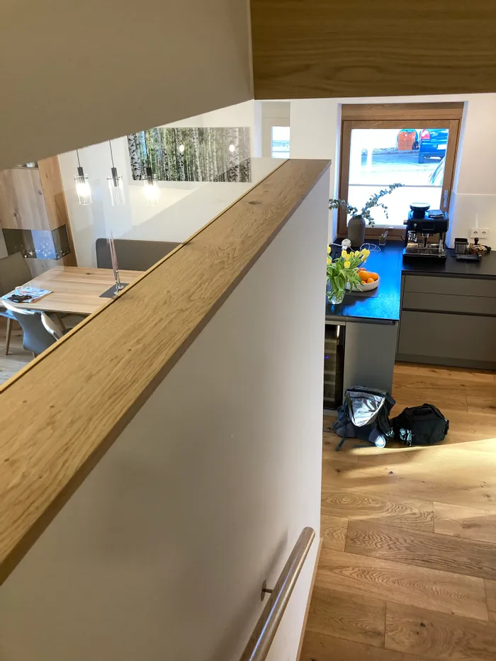 Moderne Küche mit Holzdetails, Kaffeemaschine, frischem Obst und Tulpen auf der Arbeitsplatte