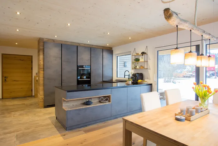 Moderne Küche mit Kücheninsel, Holzdecke, Hängelampen und Tulpen auf Holztisch