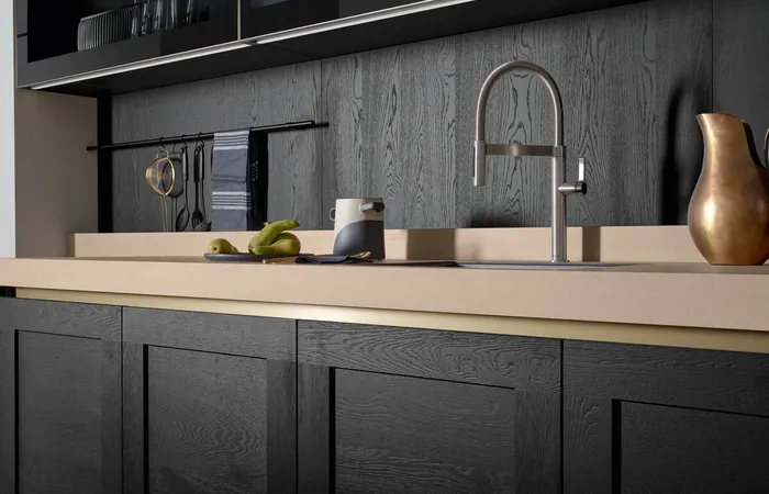 Moderne Küche mit schwarzer Holzfront, beiger Arbeitsplatte und Edelstahlarmatur