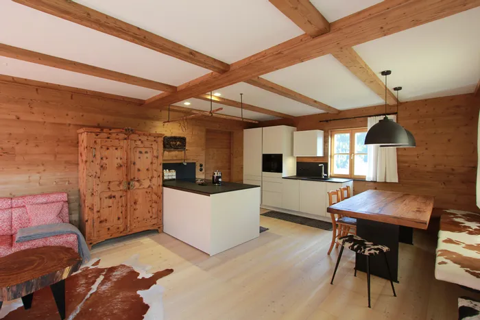 Moderne offene Küche mit Holzwänden, Essbereich und rustikaler Einrichtung im Alpenstil