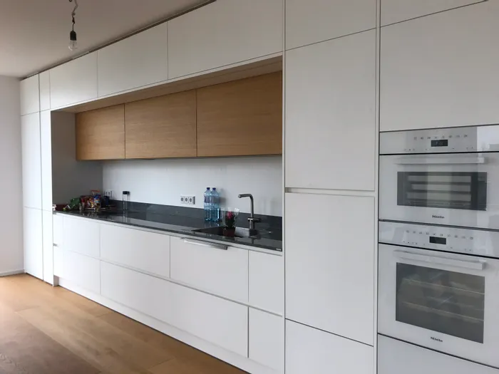 Moderne Einbauküche mit weißen Schränken, Holzdetails und Miele Einbaugeräten