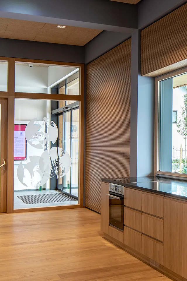 Moderne Holzküche mit schwarzer Arbeitsplatte und Blick auf Eingang mit Glastür