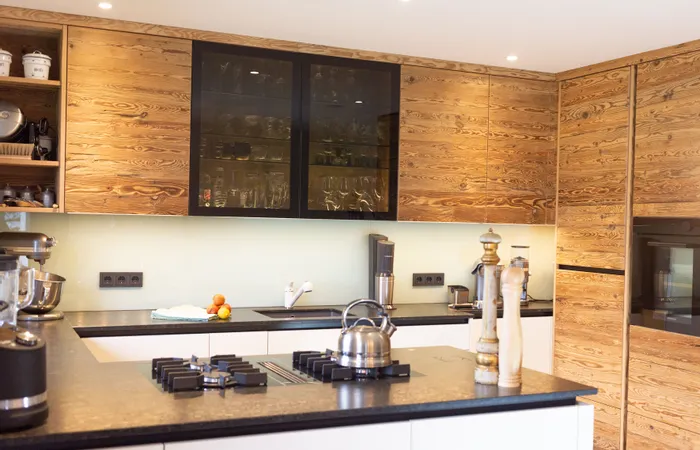 Moderne Küche mit Holzfronten, schwarzer Arbeitsplatte und Edelstahlgeräten