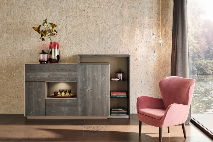 Wohnzimmer mit rosa Sessel, grauer Holzkommode und dekorativen Vasen vor Fenster mit Seeblick