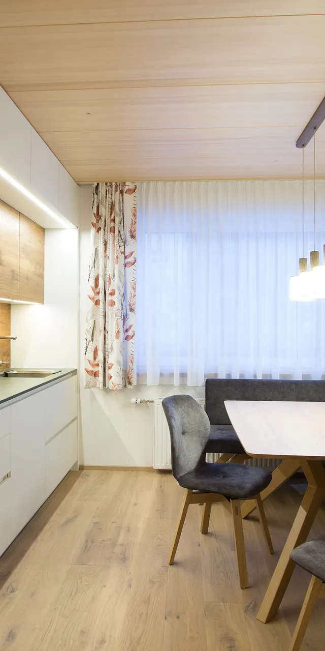 Moderne Einbauküche mit Holzdecke, Eckbank, Esstisch und dekorativen Vorhängen