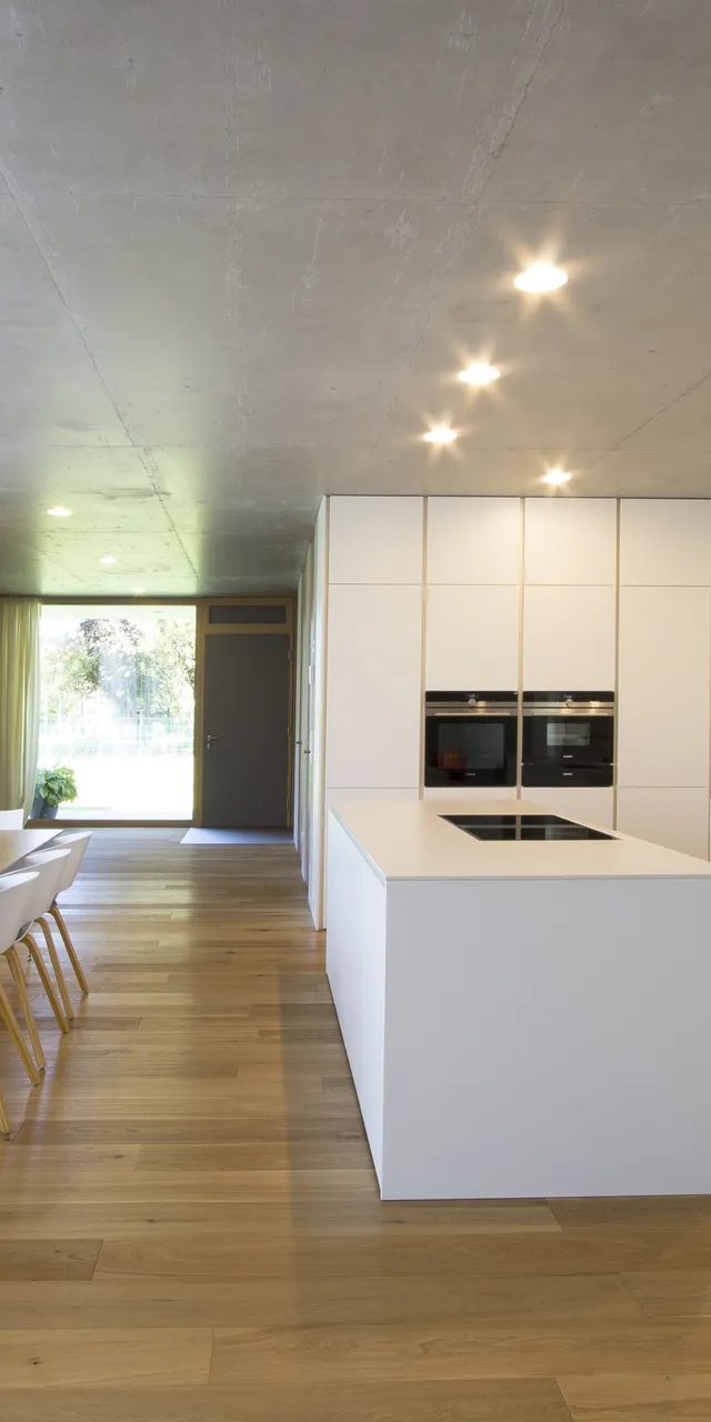 Moderne offene Küche mit weißer Kücheninsel, Esstisch und Holzfußboden