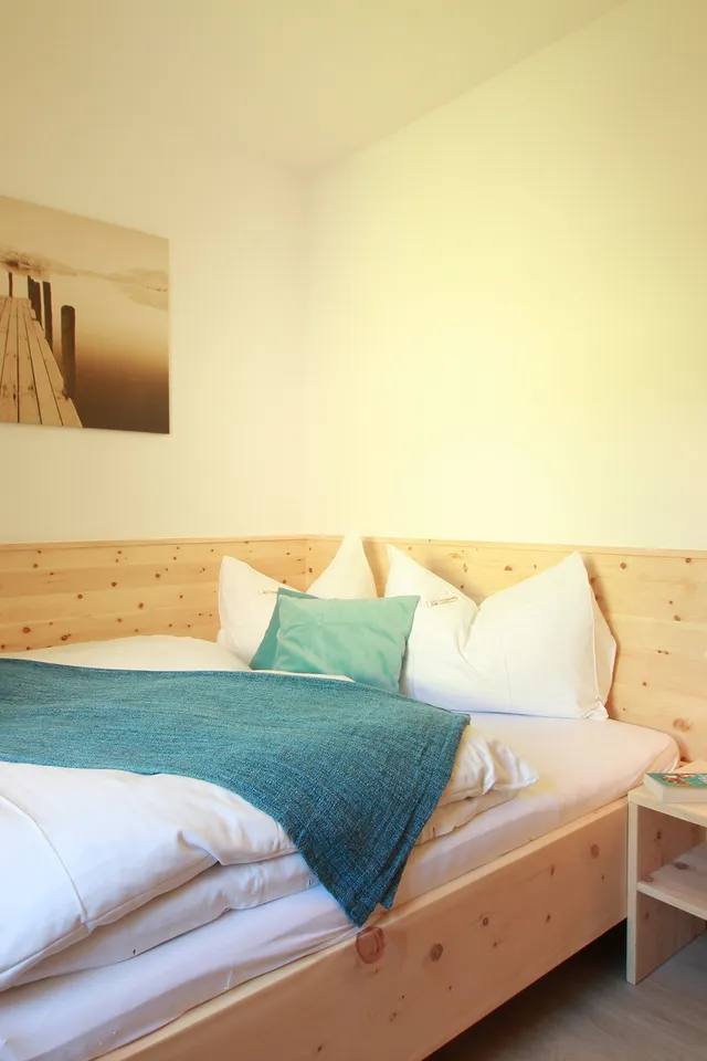 Gemütliches Schlafzimmer mit Holzbett, Nachttisch und stimmungsvollem Foto an der Wand