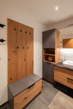 Modernes Badezimmer mit Holz- und Betonelementen, Wandhaken und Aufbewahrungsmöbeln