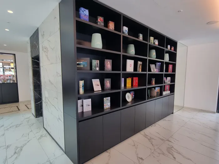 Modernes Foyer mit schwarzem Regal voller Bücher, Dekorationen und Marmorboden