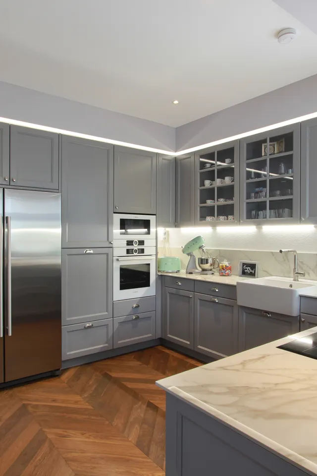 Moderne Küche mit grauen Schränken, Marmorarbeitsplatte und Edelstahlgeräten