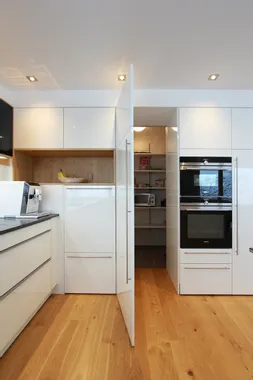 Moderne weiße Küche mit offenem Vorratsraum und integrierten Geräten