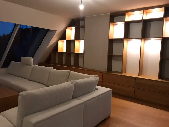 Modernes Wohnzimmer mit cremefarbenem Sofa und beleuchteten Holzregalen an der Wand