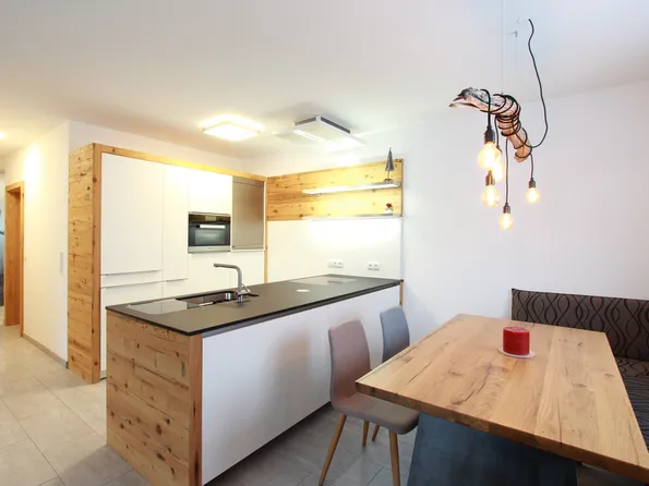 Moderne Küche mit Holzverkleidung, Kücheninsel, Esstisch und Hängelampen im skandinavischen Stil