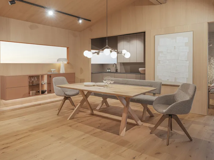 Modernes Esszimmer mit Holztisch, gepolsterten Stühlen und offener Küche im skandinavischen Stil