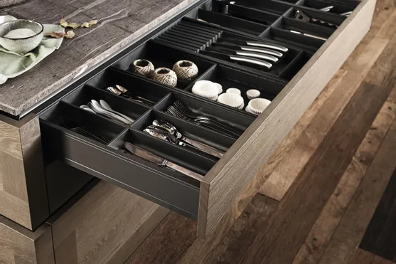 Geöffnete Küchenschublade mit Besteckeinsatz und ordentlich sortiertem Küchenzubehör