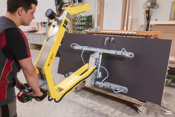 Handwerker bedient Vakuumhebegerät zum Heben großer Platten in einer Werkstatt