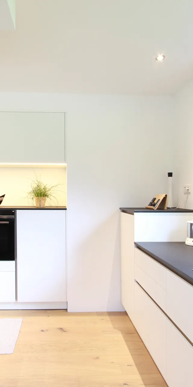 Moderne weiße Einbauküche mit schwarzer Arbeitsplatte und großem Fenster