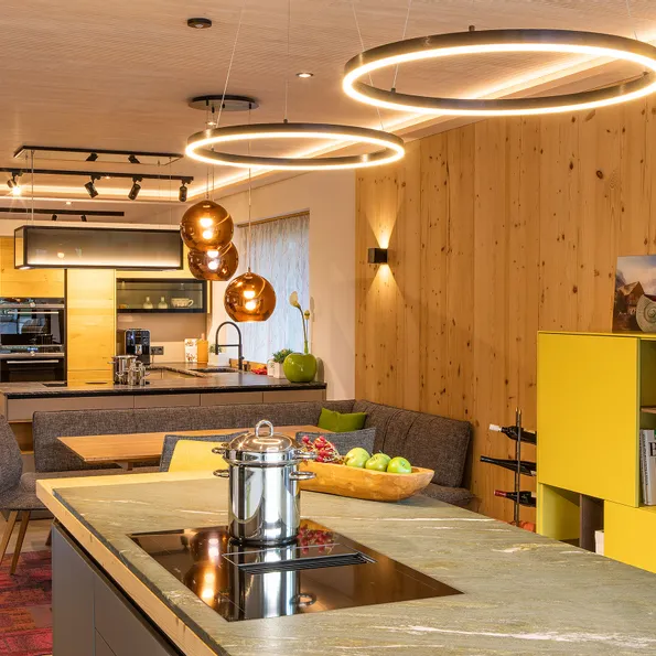 Moderne offene Küche mit Holzverkleidung, Kochinsel und eleganten Hängelampen