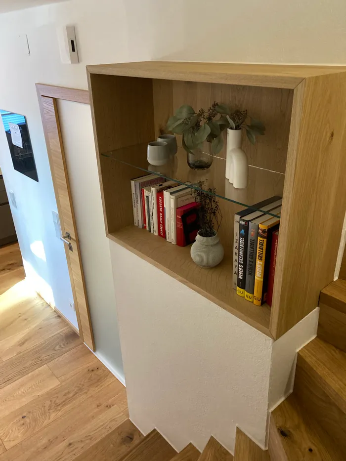 Offenes Regal aus Holz mit Büchern und Vasen neben moderner Treppe im Innenbereich