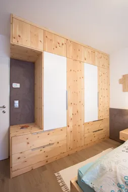 Einbauschrank aus hellem Holz mit weißen Türen in einem modernen Schlafzimmer