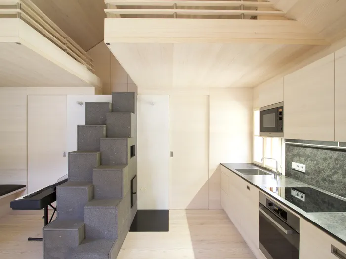 Moderne Einbauküche mit hellem Holz, grauer Steintreppe und Hochbett im minimalistischen Design