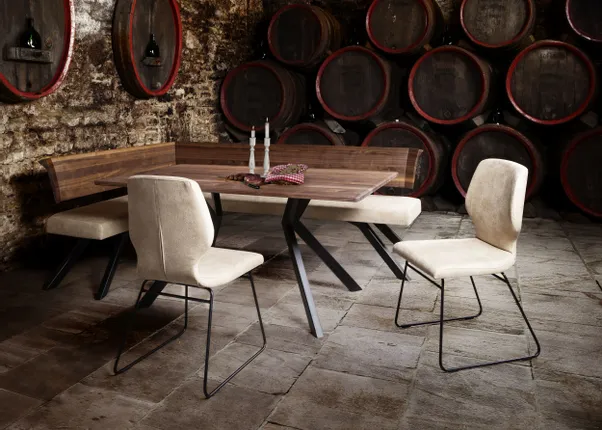 Rustikaler Weinkeller mit Holztisch, Polsterstühlen und Weinfässern an der Steinwand